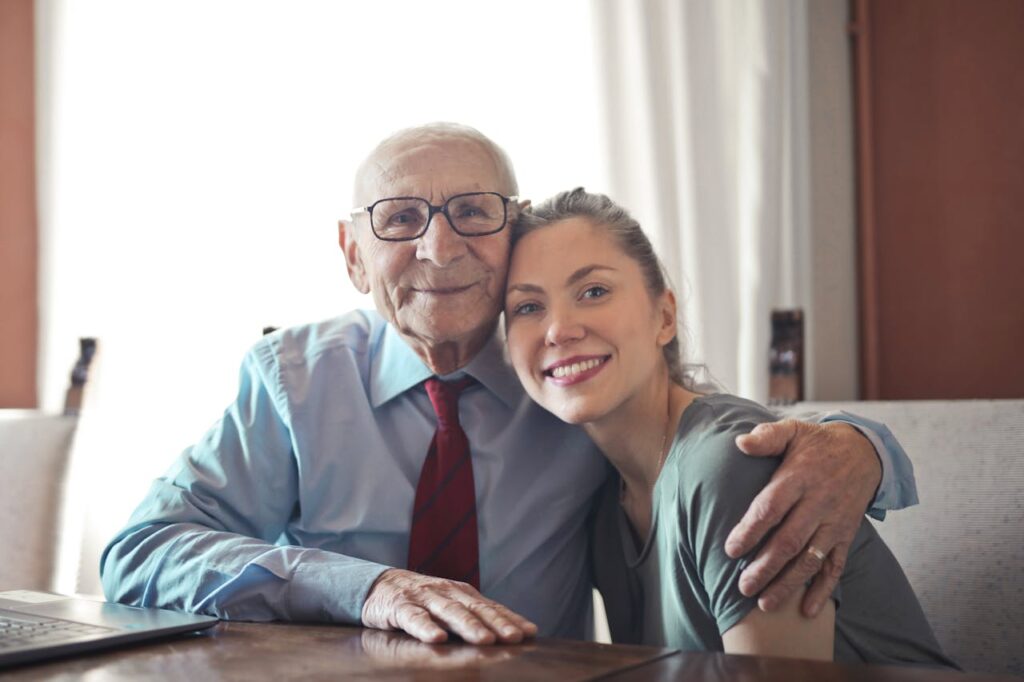 A joyful elderly man and young woman sharing an affectionate embrace indoors.